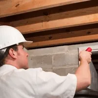 Termite inspection technician checking a basement wall and framing for termite activity in New Haven, CT